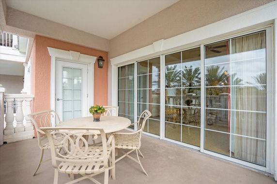 Outdoor patio area with a round table and chairs, adjacent to a building with sliding glass doors.