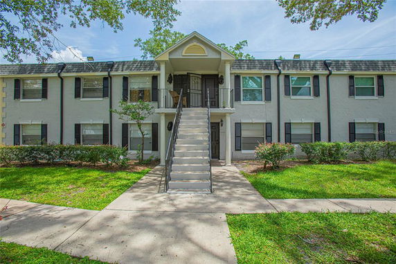 Front view of a two-story residential building with an exterior staircase leading to the second floor.