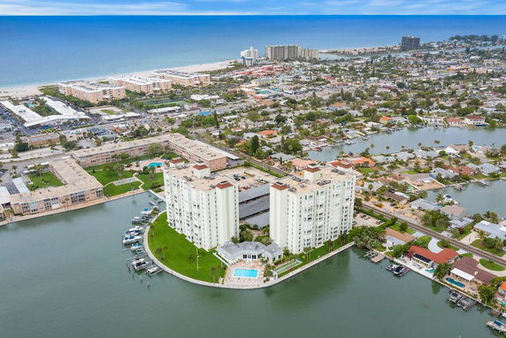 Aerial view of a waterfront apartment complex by the sea, with surrounding residential and urban areas.