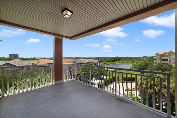 View from a balcony overlooking rooftops, greenery, and water.