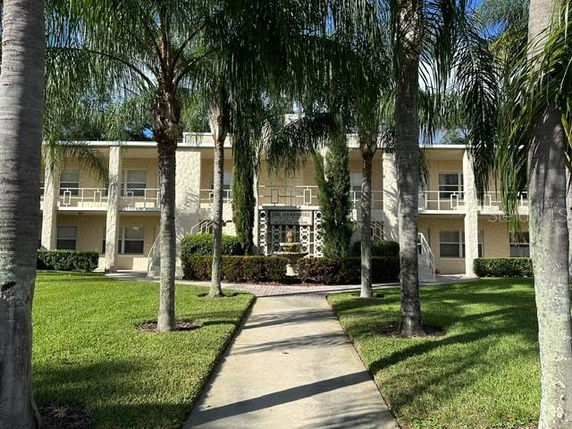Front view of a two-story building with a walkway and palm trees.