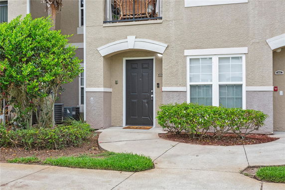 Front view of a townhouse entrance with a dark door and adjacent windows.