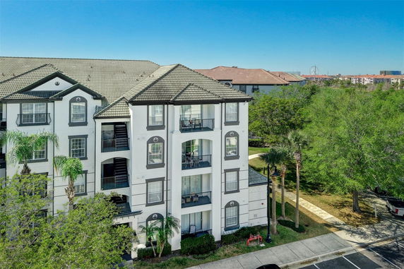 Front view of a multi-story apartment building with balconies and tiled roof.