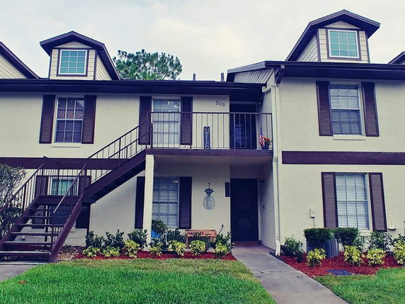 Front view of a two-story residential building with brown accents and external stairs.