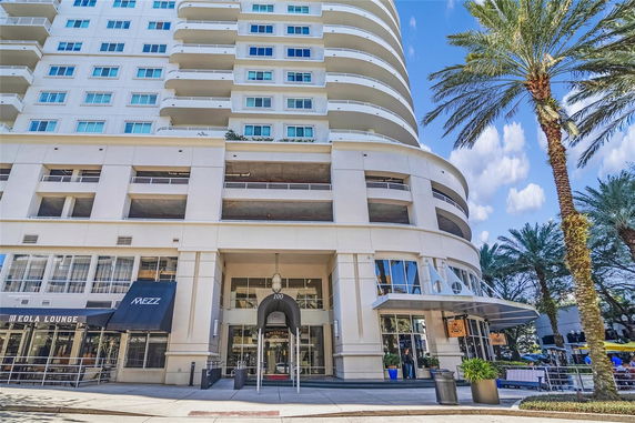 Front view of a multi-story building with balconies and commercial storefronts at the ground level.