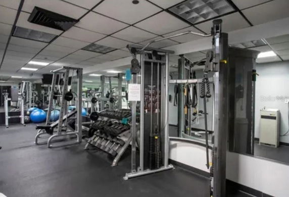 Interior view of a gym with various exercise equipment, including weight racks and fitness machines.