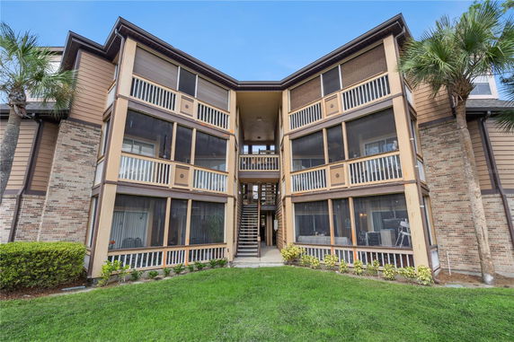 Front view of a multi-story building with enclosed balconies and central staircase.