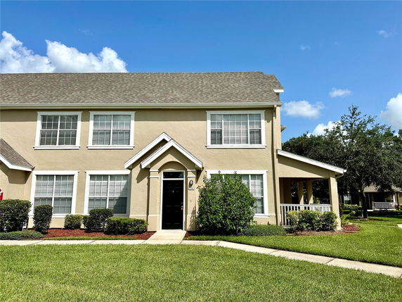 Front view of a two-story beige house with a gable roof and multiple windows.