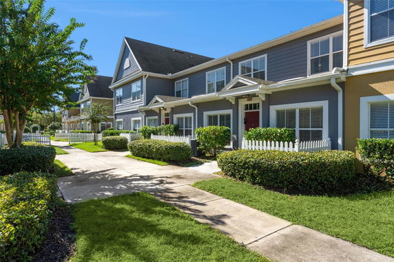 Front view of a two-story row of houses with white picket fences.