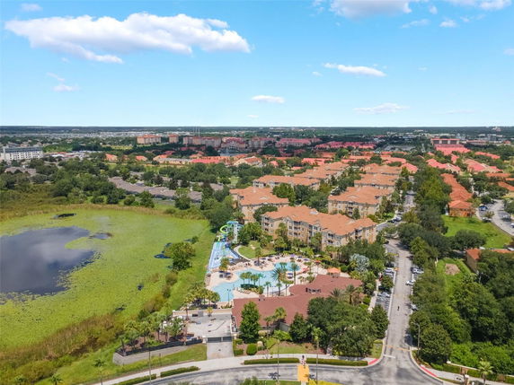 Panoramic view of a residential area with multiple apartment buildings surrounded by greenery and a nearby lake.