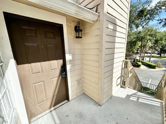 Exterior entryway of a residential building with a brown door and light fixture.
