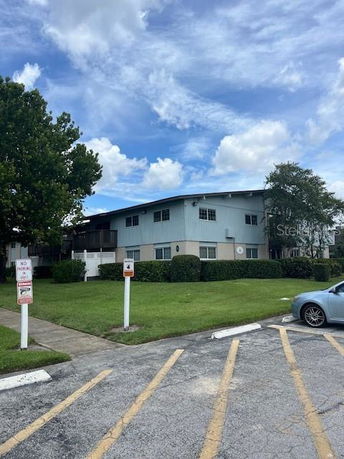 Front view of a two-story building with light blue siding and a parking area in the foreground.