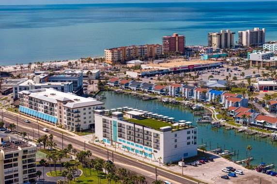 Panoramic view of a coastal area with multiple buildings, waterfront properties, and a beach in the distance.