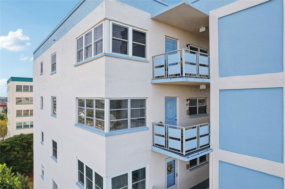 Corner view of a multi-story building with balconies and blue accents.