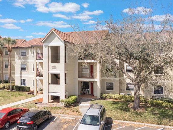 Front view of a multi-story apartment building with parking area in front.