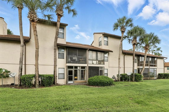 Front view of a multi-story building with screened balconies and palm trees.