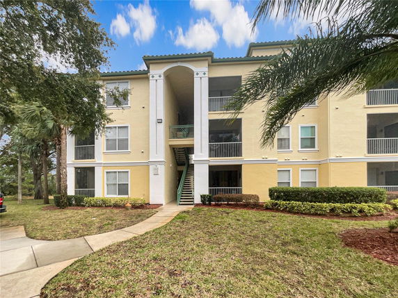 Front view of a three-story residential building with balconies and arched entrance.