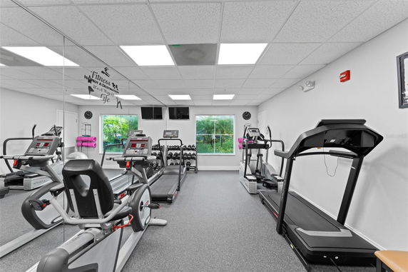 Indoor gym area with exercise equipment including treadmills, stationary bikes, and weights.