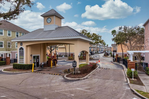 Front view of a gated entrance with a clock tower over a roadway.