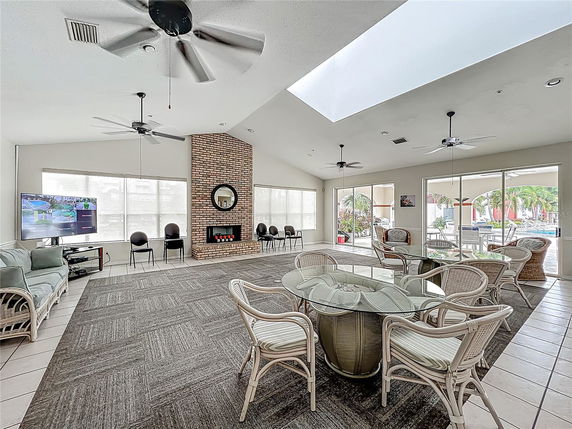 Indoor club house area with seating, ceiling fans, and a brick fireplace.