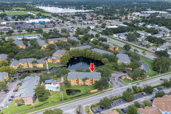 Aerial view of a residential area with multiple buildings and a small lake surrounded by trees.