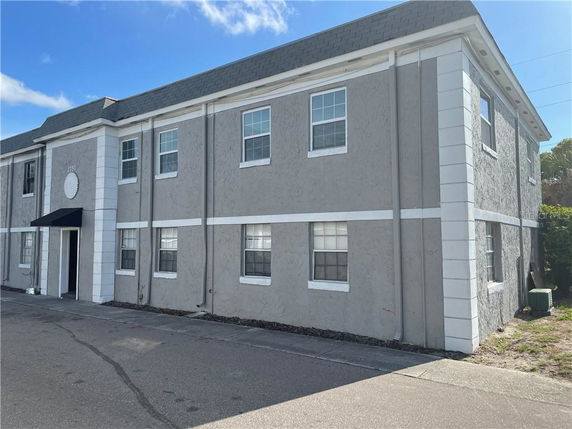 Front view of a two-story house with a flat roof and multiple windows.