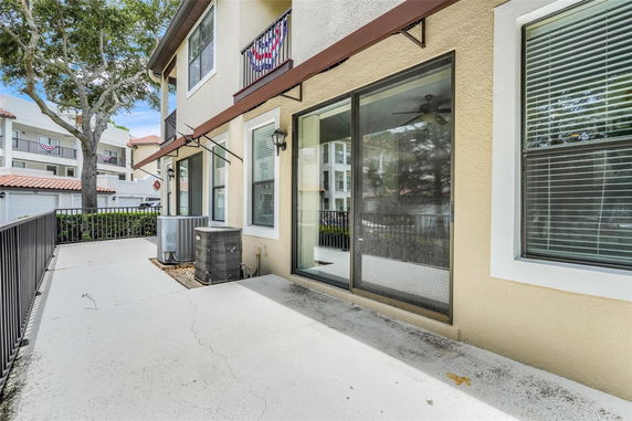 Side view of a multi-story house with large windows and air conditioning units on the ground.