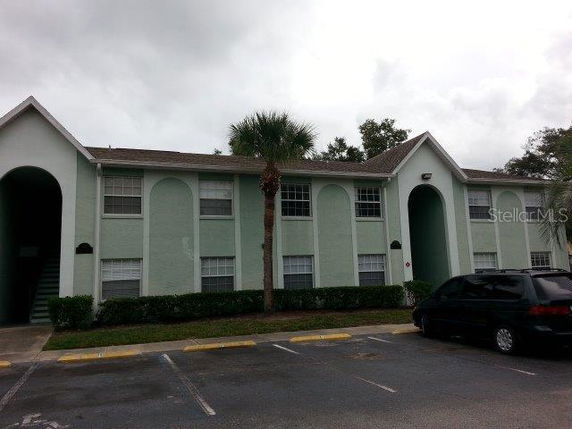 Front view of a two-story apartment building with arched entrances and a green exterior.