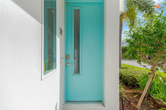 Front view of a house with a bright blue front door and white exterior walls.