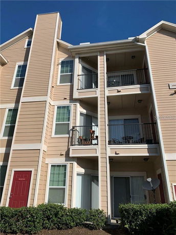 Front view of a multi-story apartment building with balconies and a red door.