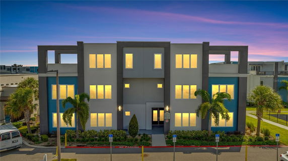 Front view of a modern three-story building with illuminated windows.