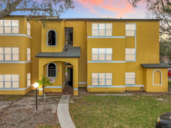 Front view of a yellow three-story building with multiple windows and an entrance archway.