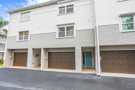 Front view of a multi-story building with multiple garages and a blue entry door.