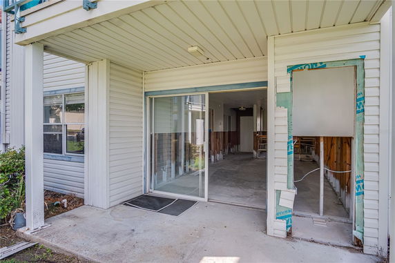 Side view of a house with sliding glass doors and siding under construction.