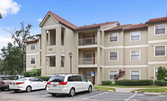 Front view of a multi-story residential building with balconies and parking area.