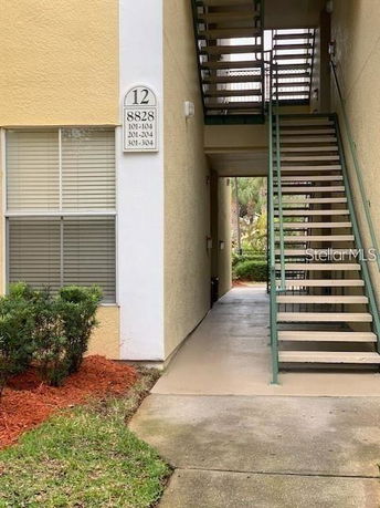 Exterior stairway of a multi-story building with a visible entrance and apartment numbers.