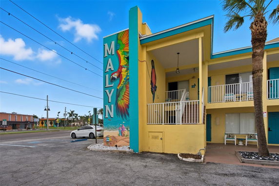 Front view of a two-story building with colorful murals and a balcony.
