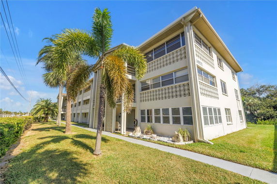 Front view of a three-story residential building with tropical landscaping.