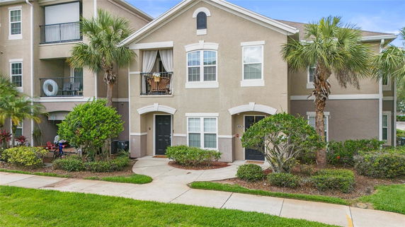 Front view of a multi-story residential building with balconies and palm trees.