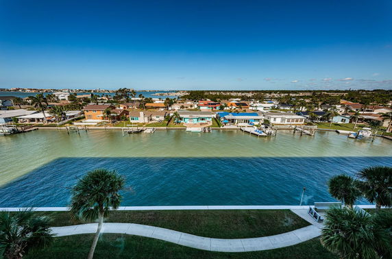 Wide angle view of a coastal residential area with houses, water, and clear sky.