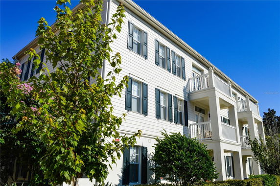 Front view of a three-story building with white siding and multiple balconies.