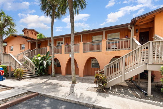 Front view of a two-story apartment building with stairs leading to the upper level.