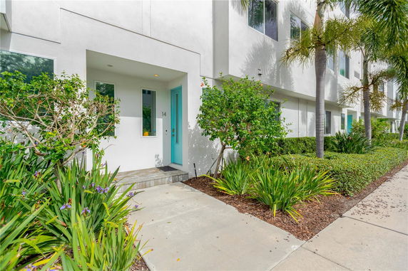 Front view of a modern townhouse with white exterior and a blue door.