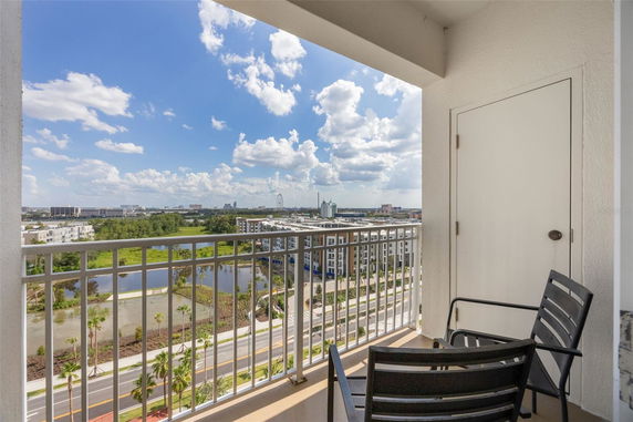 Balcony view overlooking urban landscape with buildings and a Ferris wheel in the distance.