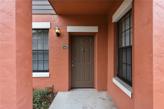 Front view of an orange-colored building with a brown door and windows.