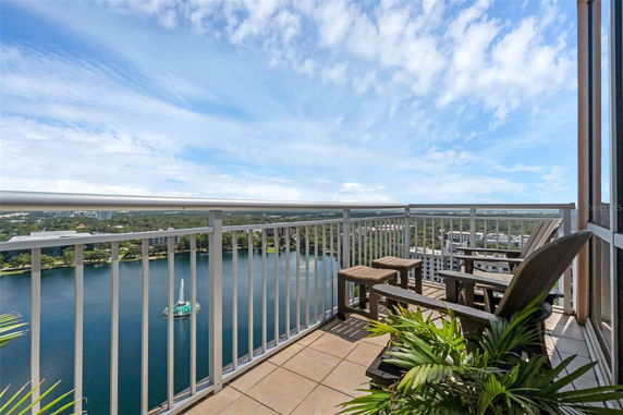Balcony with seating offering a panoramic view of a lake and surrounding cityscape.