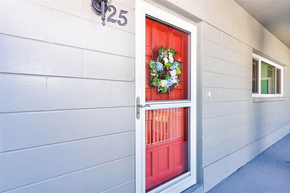 Front view of a building entrance with a red door adorned with a floral wreath.