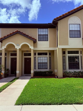 Front view of a two-story townhouse with arches and a well-maintained lawn.