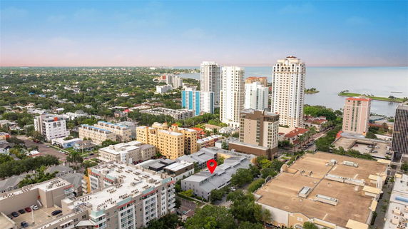 Panoramic view of a cityscape with various high-rise buildings and greenery, overlooking a body of water.