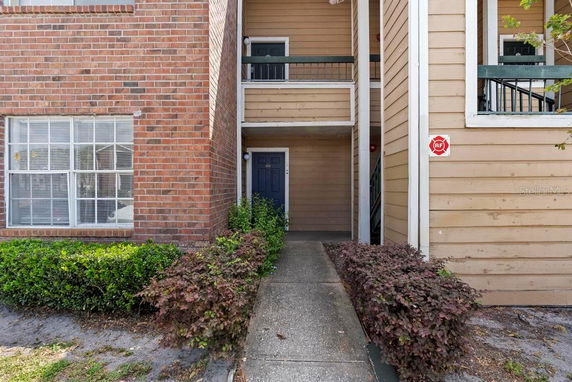 Entrance of a multi-story apartment building with brick and wood siding.